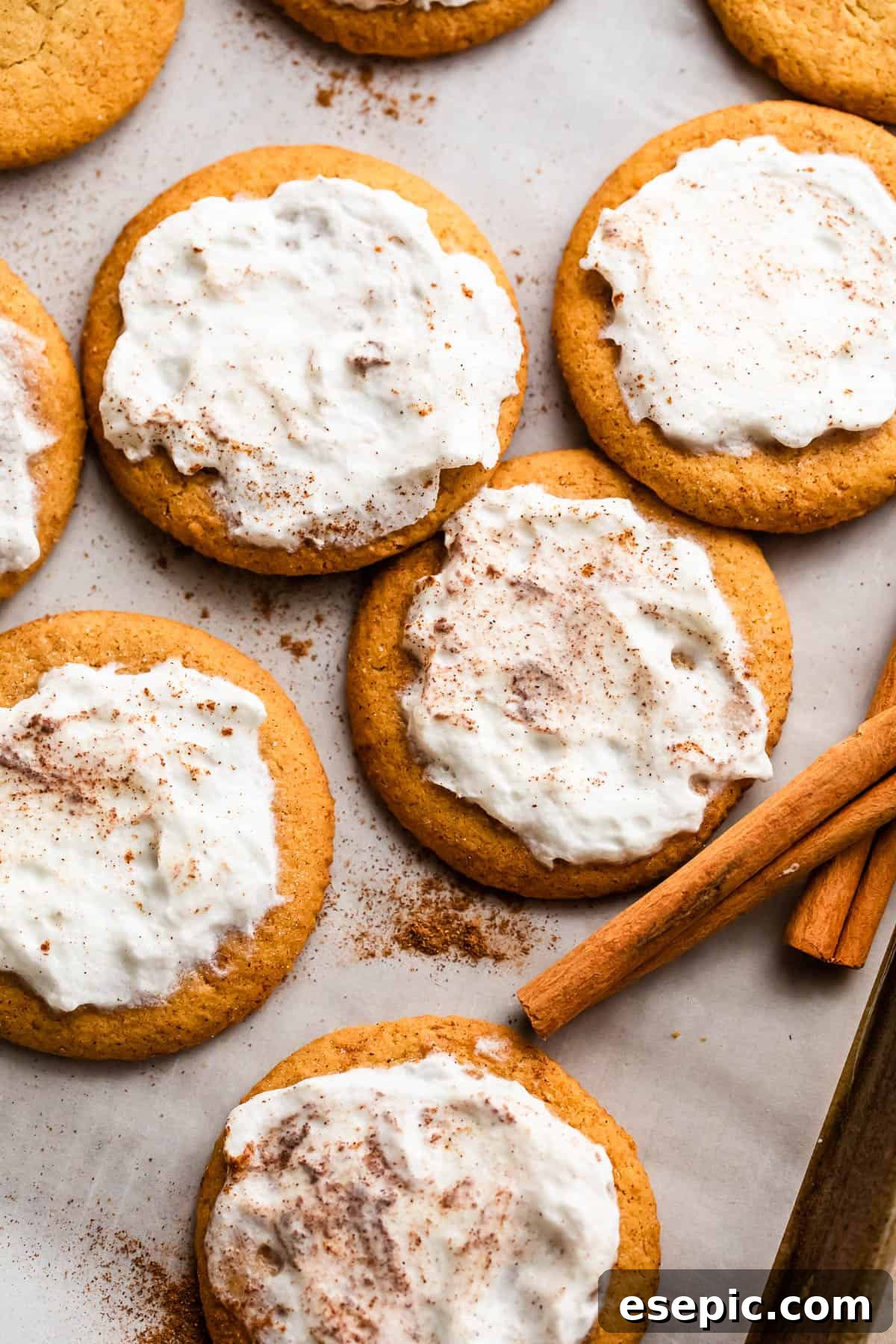 Pillowy Pumpkin Spice Cookies 2 overhead shot of pumpkin cookies topped with cream cheese frosting and arranged on a baking sheet lined with parchment paper.