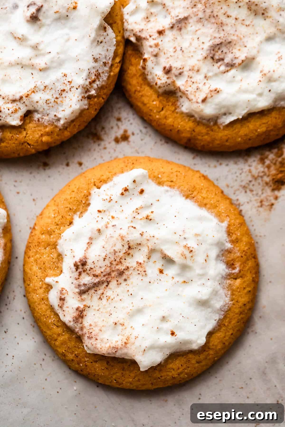 Pillowy Pumpkin Spice Cookies 4 overhead shot of three pumpkin cookies topped with cream cheese frosting.