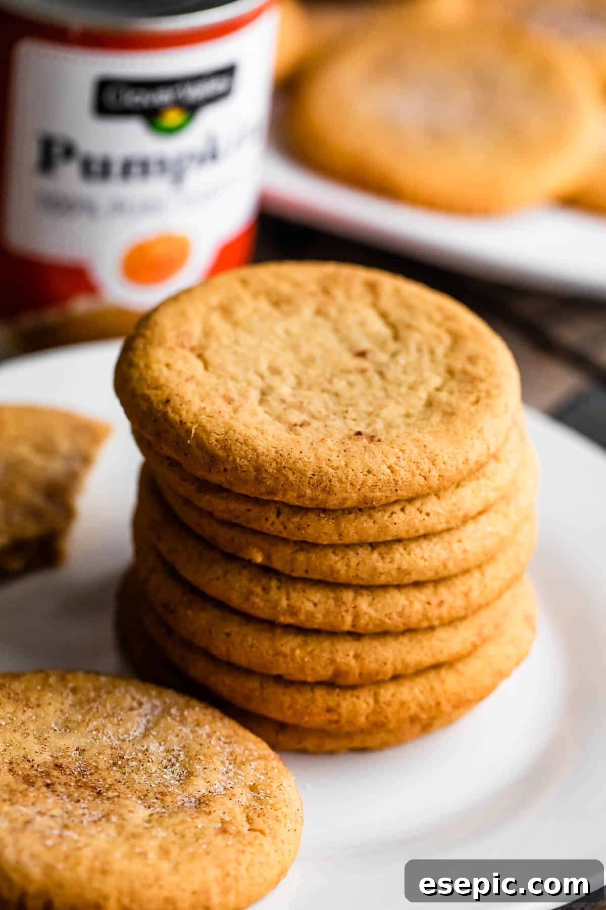 Pillowy Pumpkin Spice Cookies 6 a stack of pumpkin cookies arranged on a white plate with a can of pumpkin set right behind the plate.