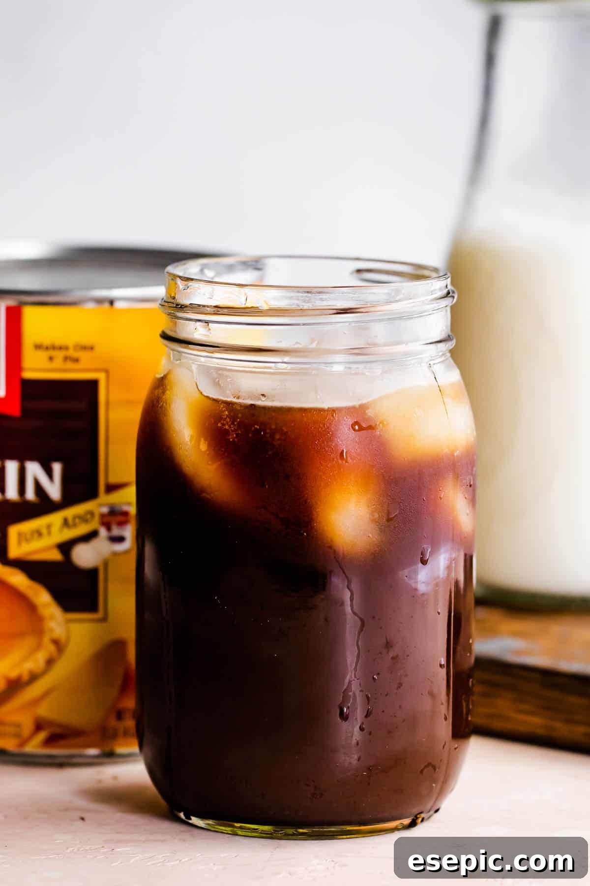 Starbucks Inspired Pumpkin Cream Cold Brew Coffee 4 jar filled coffee and ice, with a pumpkin can placed right behind it.