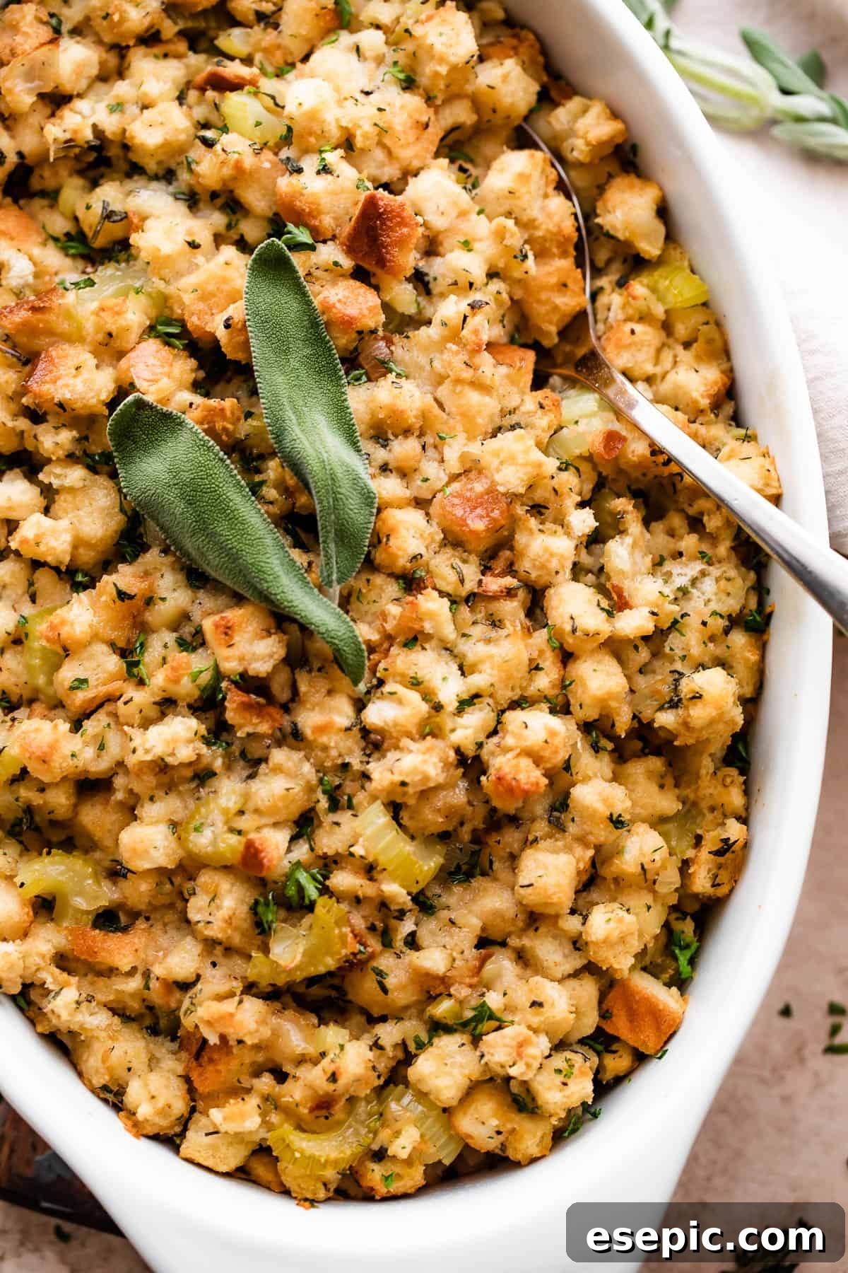 Savory Herb Stuffing Made Simple 3 Fresh baked stuffing (dressing) sprinkled with sage leaves and herbs in a white dish.