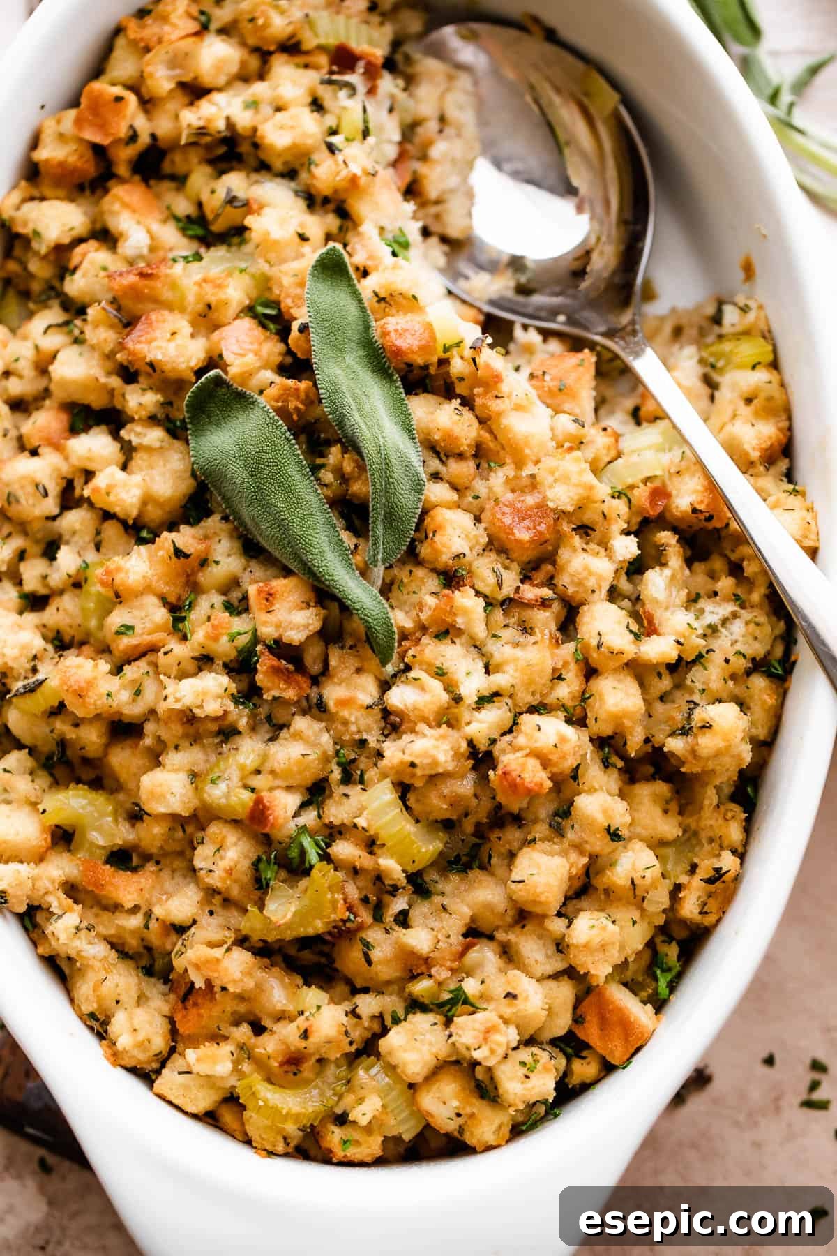 Savory Herb Stuffing Made Simple 7 overhead shot of fresh baked stuffing (dressing) sprinkled with sage leaves and herbs in a white dish.