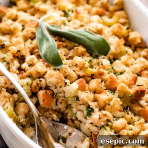 An overhead shot of a scalloped casserole dish, filled with baked bread stuffing. A serving spoon is in the dish.