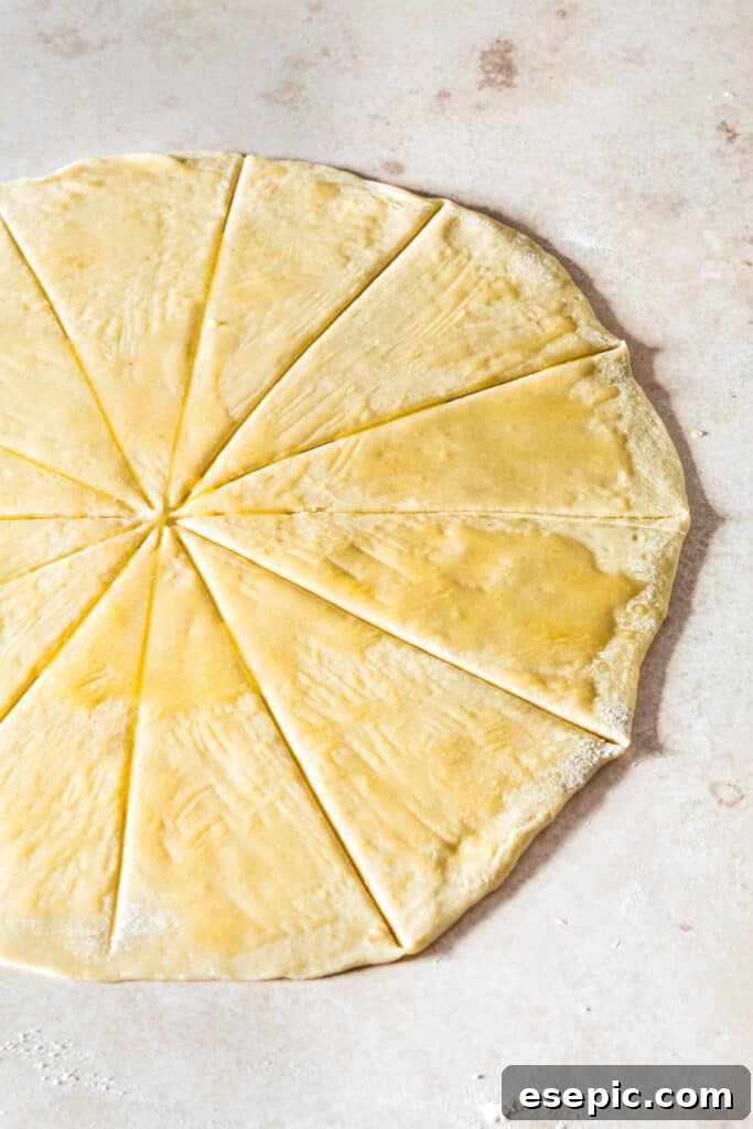 Dough meticulously rolled into a large circle and cut into twelve wedges, each generously brushed with melted butter, ready for shaping.