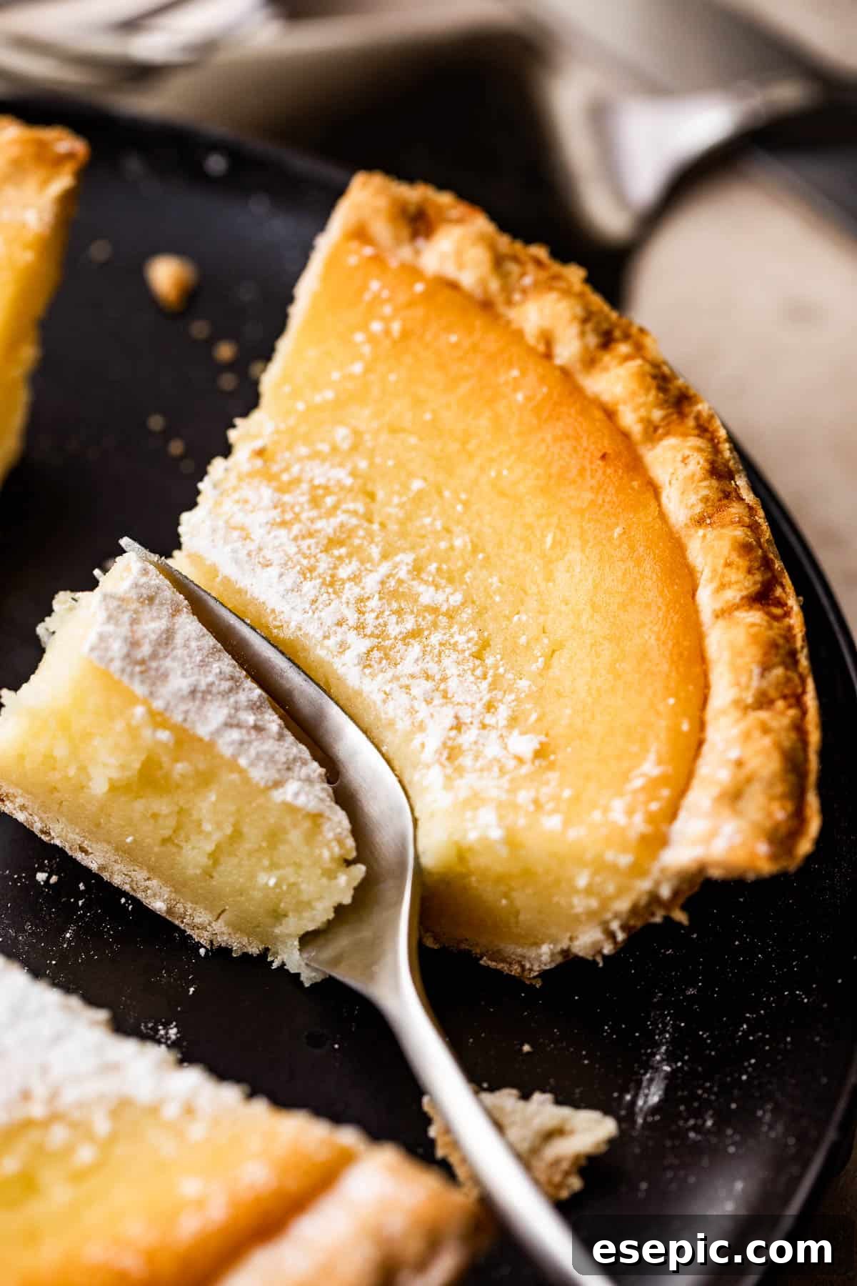 A perfectly portioned slice of buttermilk pie, artfully presented on an earthenware saucer with a small dessert fork, inviting indulgence.