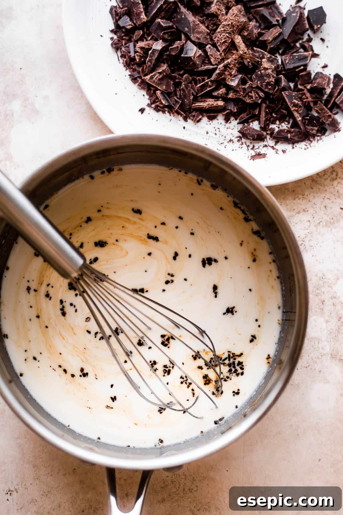 Parisian Hot Chocolate Indulgence 4 overhead shot of a saucepan filled with heavy cream and a plate with chopped chocolate placed nearby.