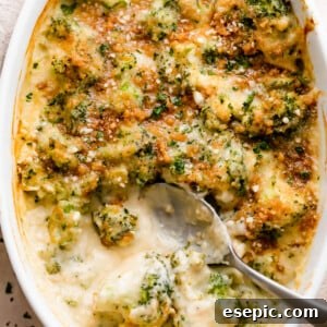 overhead shot of an oval baking dish with Cheesy Broccoli Casserole and a spoon mixing through it.
