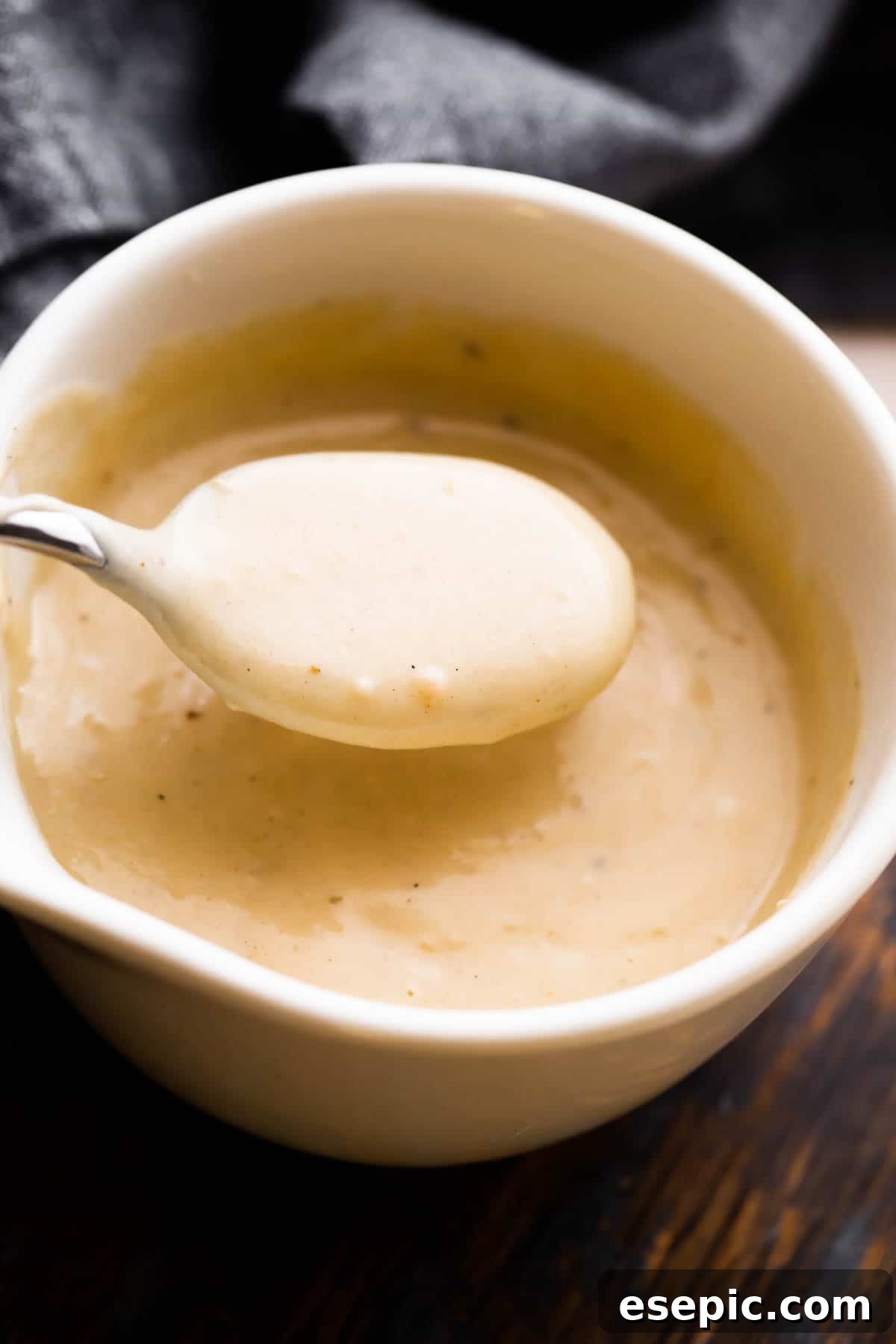Velvety Creamy Chicken Soup 6 A close-up, inviting overhead shot of a white ceramic cup filled with homemade cream of chicken soup, with a spoon gently scooping a portion, highlighting its luscious texture.