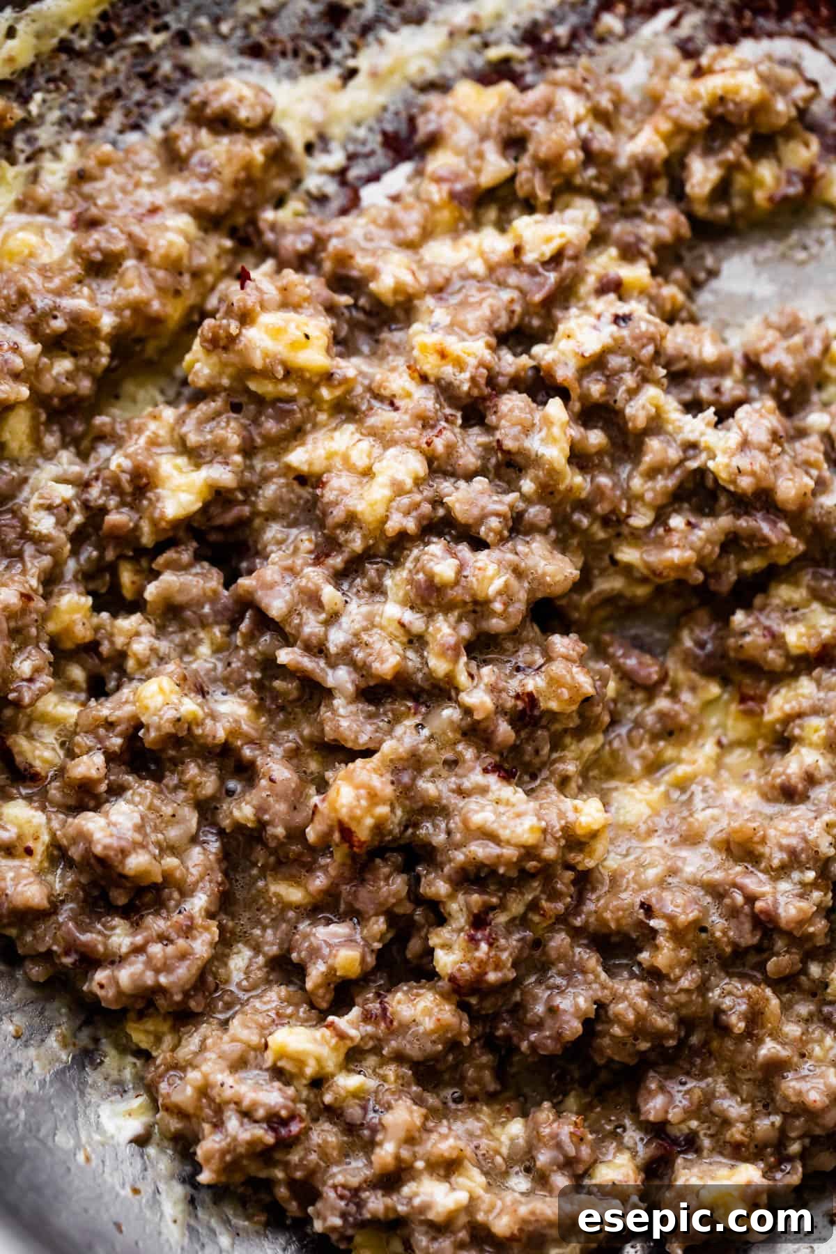 These breakfast egg cups are the perfect grab-and-go option! Italian sausage and scrambled eggs are topped with cheese and baked in a biscuit crust. Cooking ground pork sausage in a skillet, breaking it into crumbles.