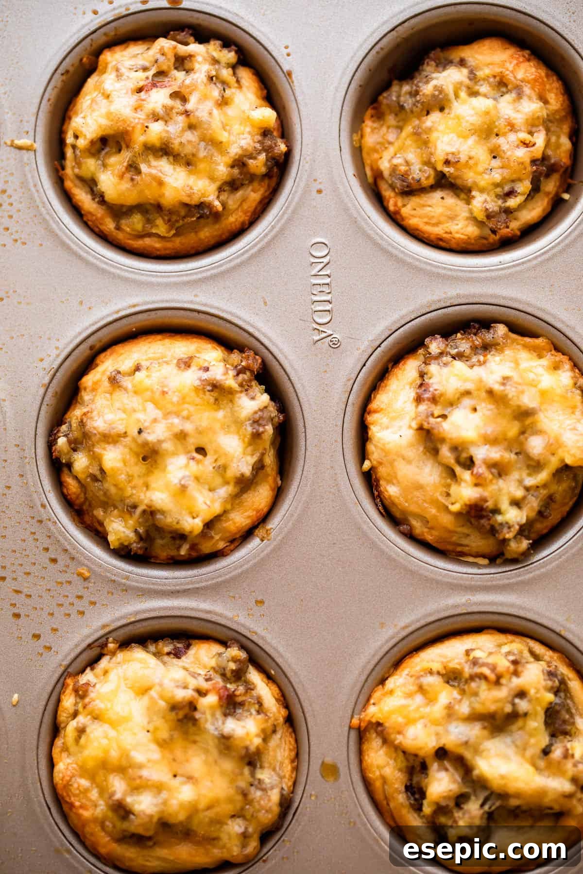 These breakfast egg cups are the perfect grab-and-go option! Italian sausage and scrambled eggs are topped with cheese and baked in a biscuit crust. Overhead picture of sausage breakfast cups in a muffin tin, ready for the oven.