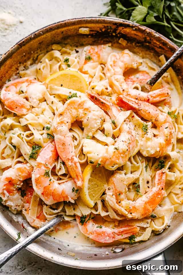 Creamy Shrimp Alfredo Pasta: Perfect for Any Occasion! A large serving bowl filled with creamy shrimp alfredo pasta, ready to be enjoyed with serving spoons.