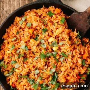 Overhead shot of a pan of Spanish rice with a wooden utensil in the pan.