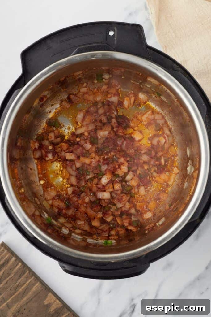 Speedy Instant Pot Mexican Rice 6 Overhead shot of an Instant Pot with vegetables and tomato paste sauteing.
