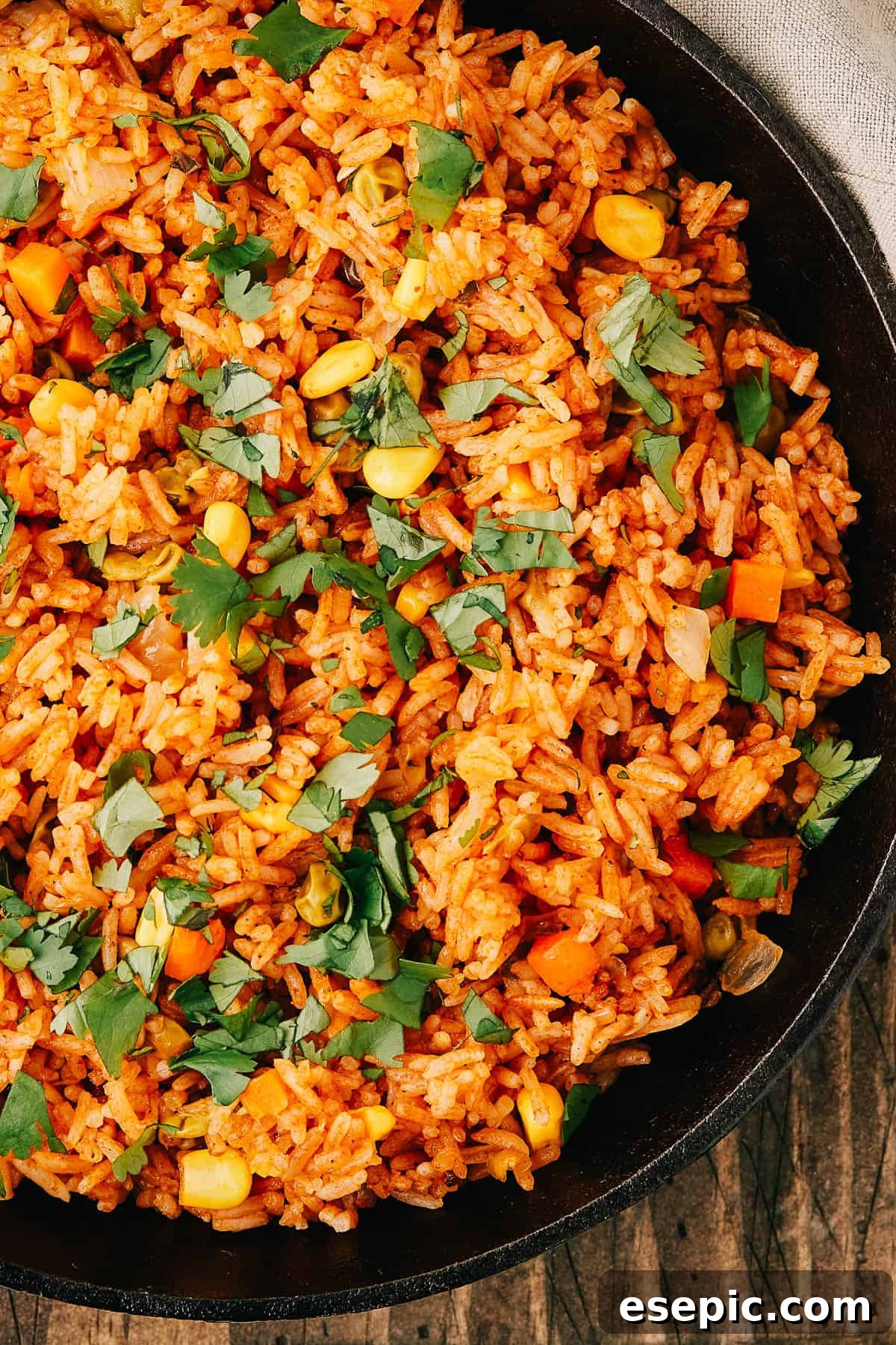 Close-up shot of a pan of seasoned rice and vegetables, garnished with fresh herbs.