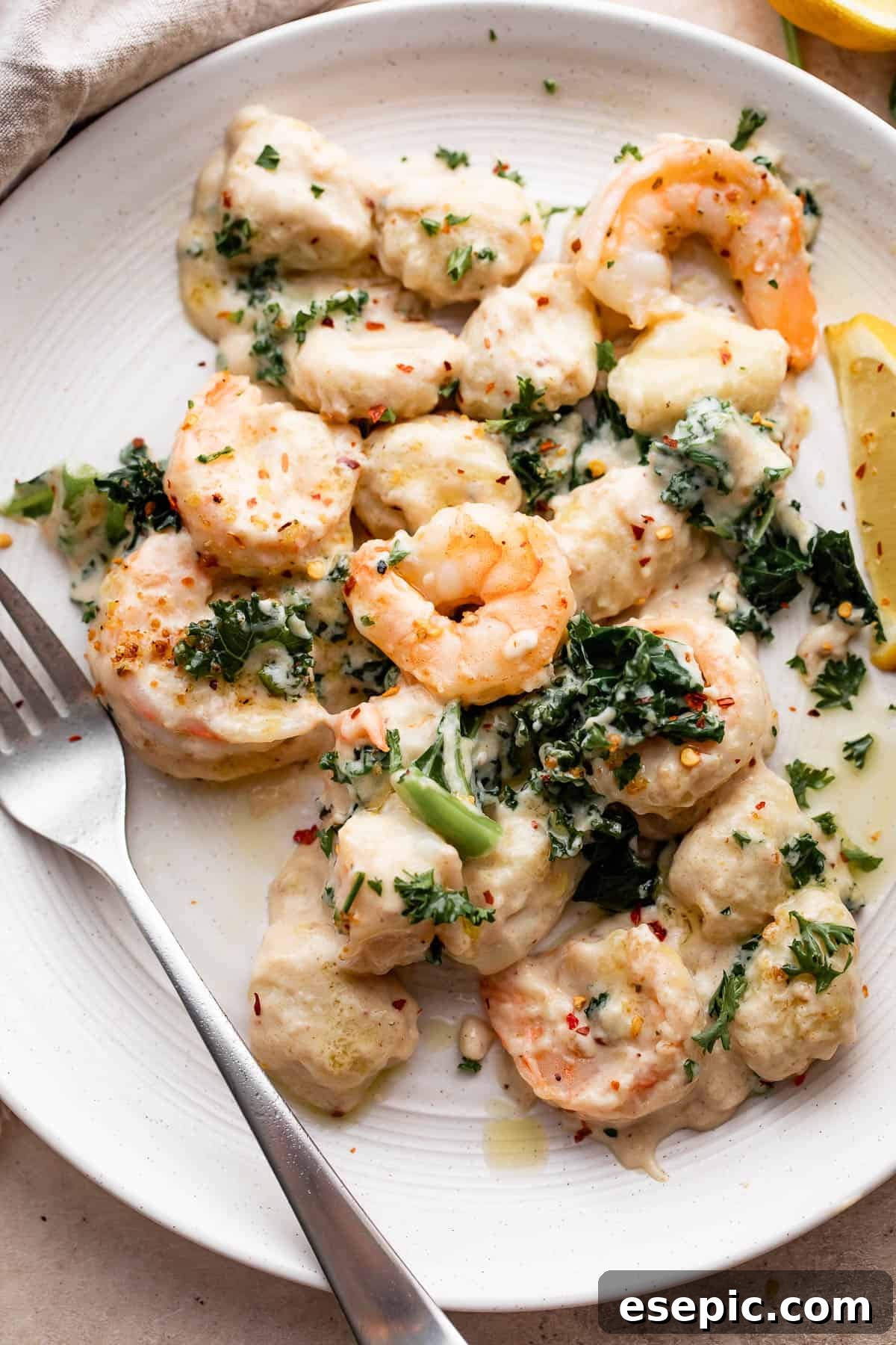 Velvety Parmesan Gnocchi with Succulent Shrimp 7 overhead shot of creamy gnocchi with shrimp served on a white plate with a fork placed to the left side on the plate.