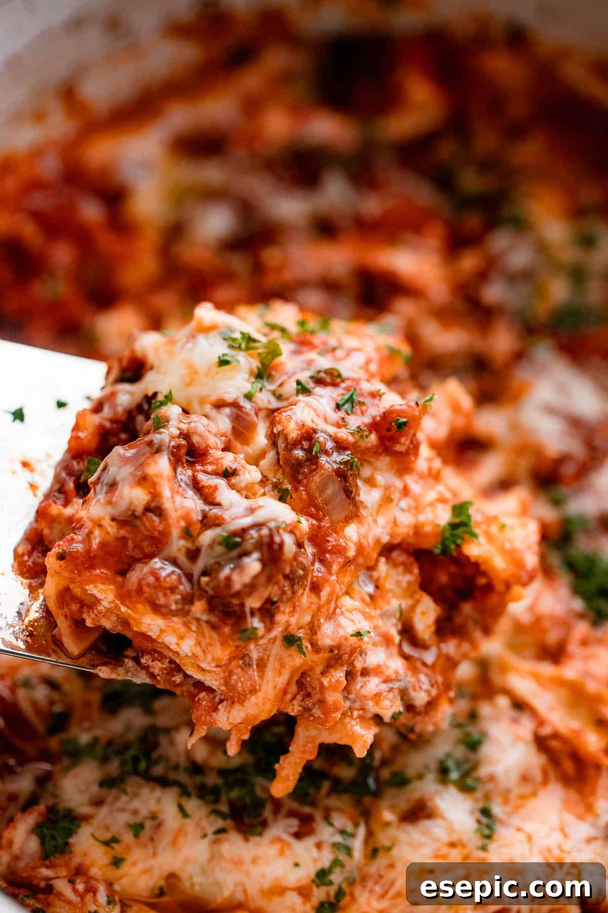 lifting up a piece of lasagna from the slow cooker.