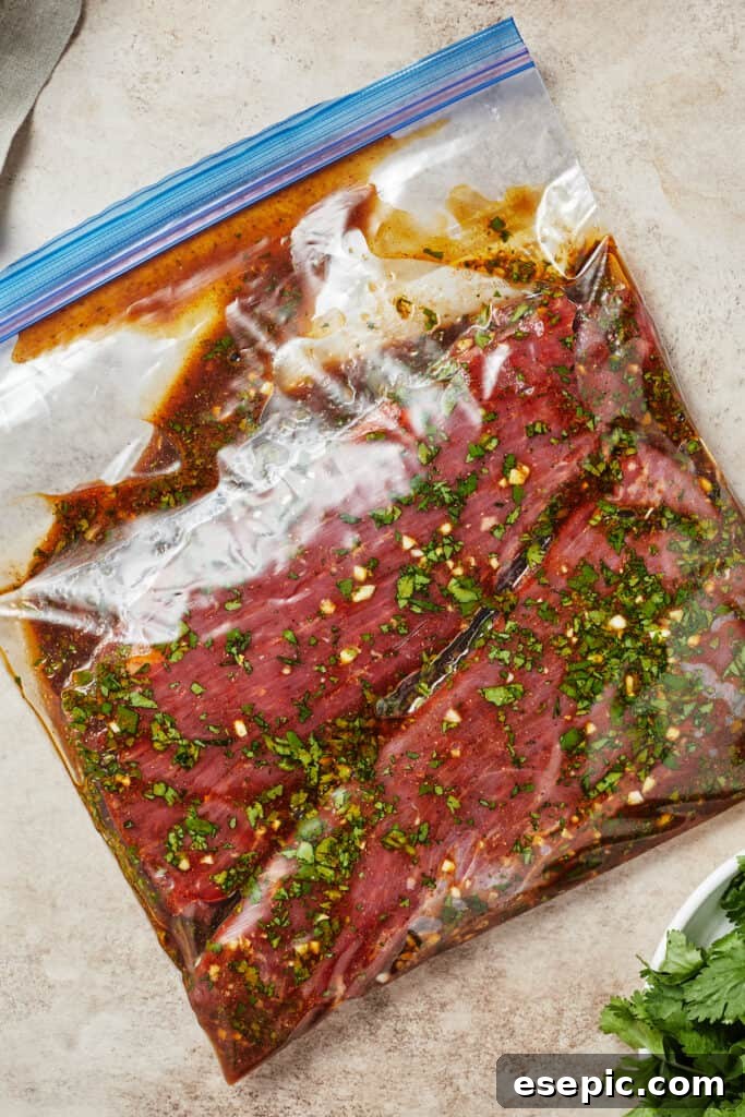 A zip-top bag containing flank steak immersed in the rich, dark marinade.