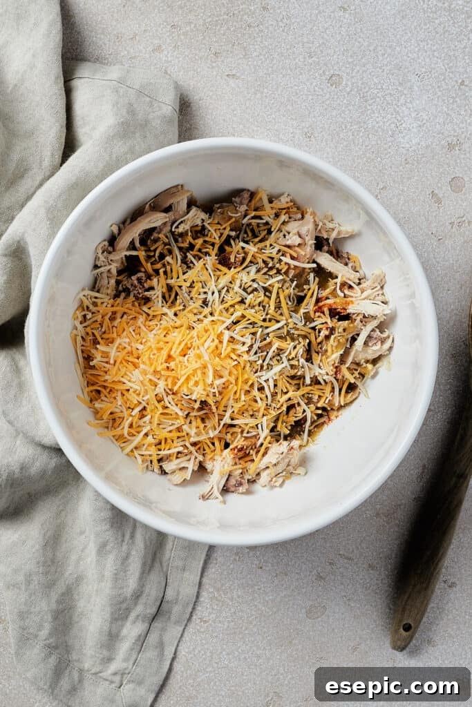 Tangy Tomatillo Chicken Enchiladas 5 A white mixing bowl with chicken, cheese, and other ingredients inside.