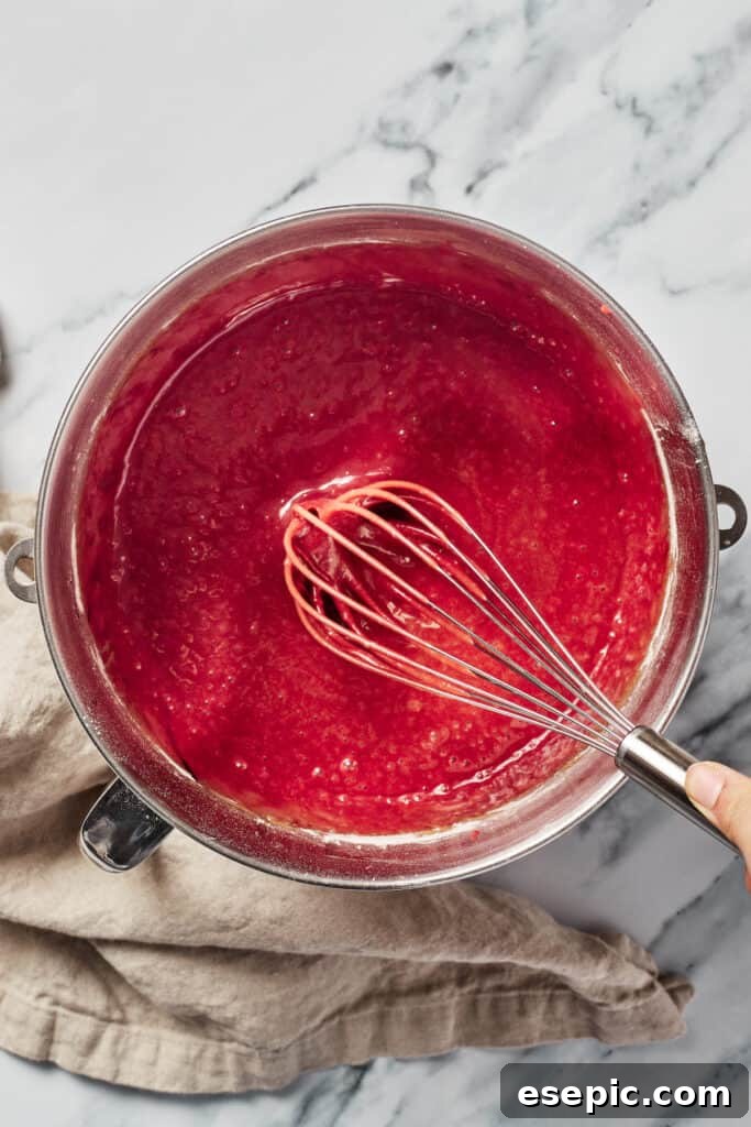 Decadent Red Velvet Dream 7 A mixing bowl filled with rich, dark red Red Velvet cake batter, with a whisk resting in it after thorough mixing.