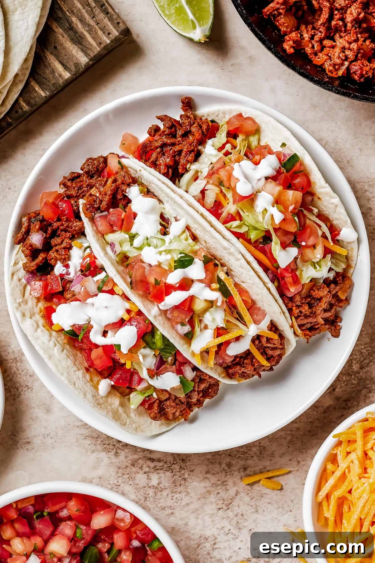 Quick and Flavorful Ground Beef Tacos 2 Three soft tacos on a plate with lime wedges.