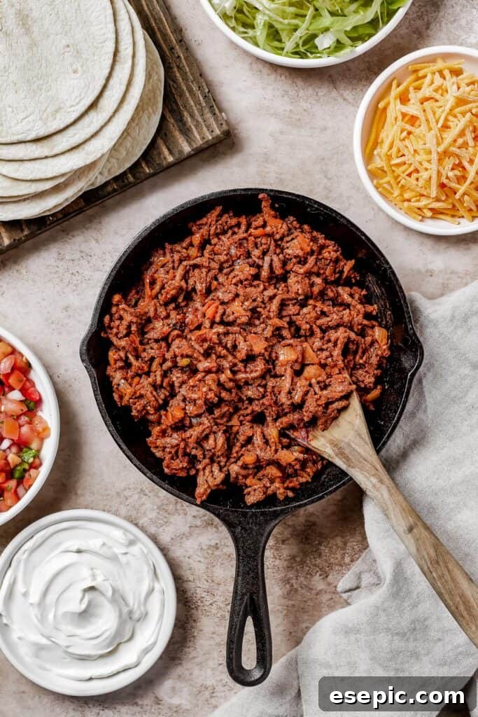 Quick and Flavorful Ground Beef Tacos 5 wooden spoon stirring through a skillet full of cooked meat for tacos.
