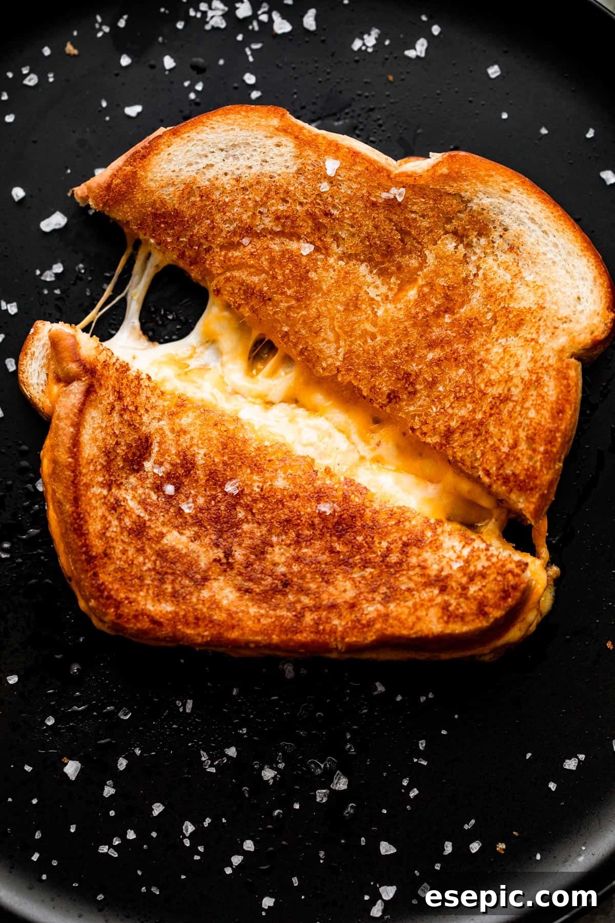 Golden Oven Baked Cheese Melts 6 A baked grilled cheese sandwich, cut in half, pulled apart to reveal long, stretchy strands of melted cheese.