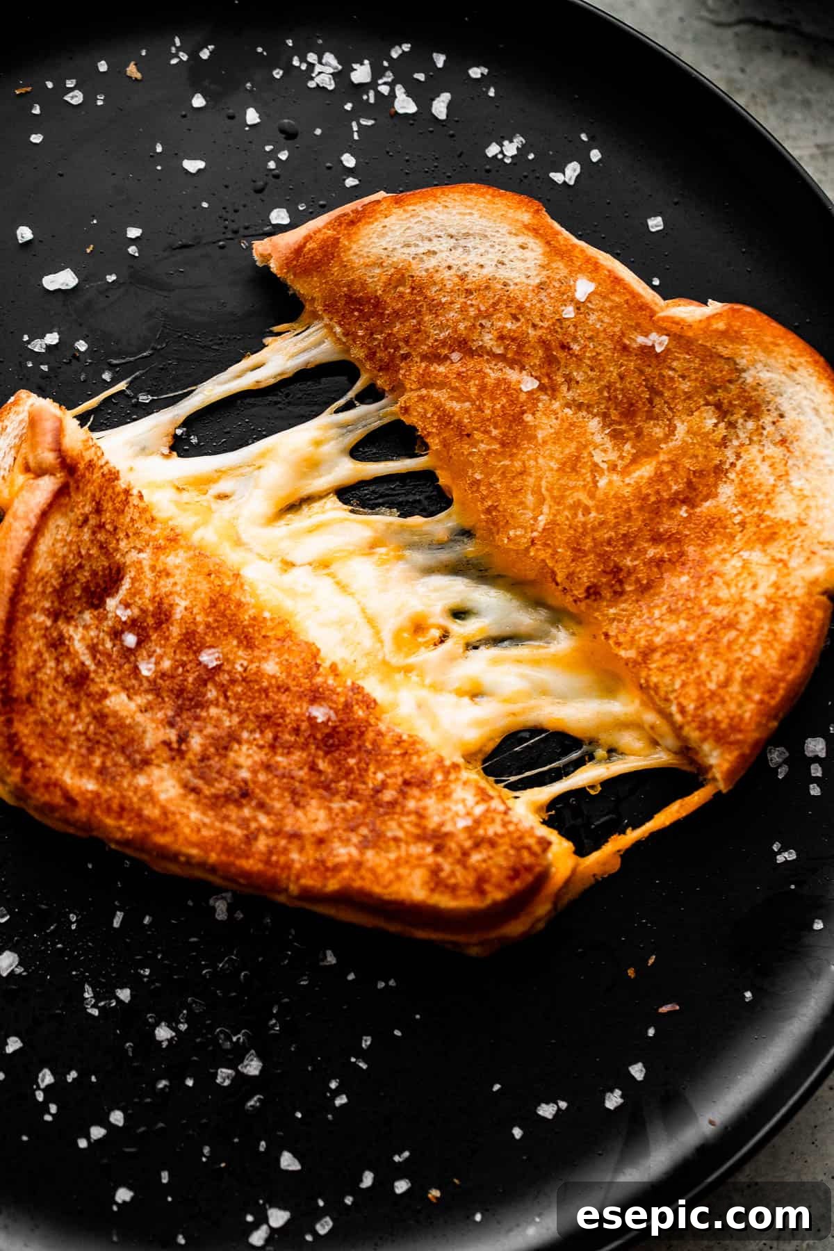 Golden Oven Baked Cheese Melts 7 A perfectly baked grilled cheese sandwich, pulled apart to reveal an abundance of melted, stringy cheese between two golden slices of bread.