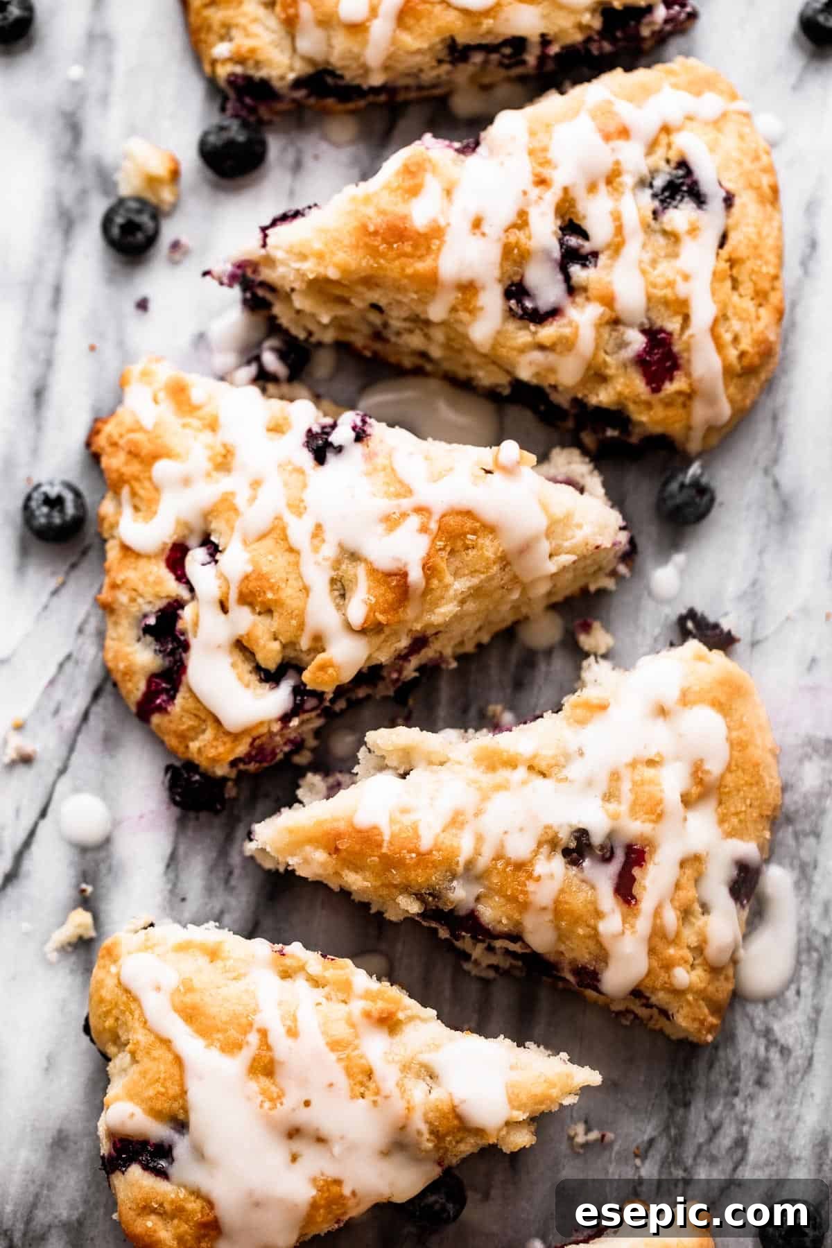 These Blueberry Scones are deliciously moist and easy to make with real, wholesome ingredients. overhead shot of blueberry scones arranged in a row on top of a marble slab