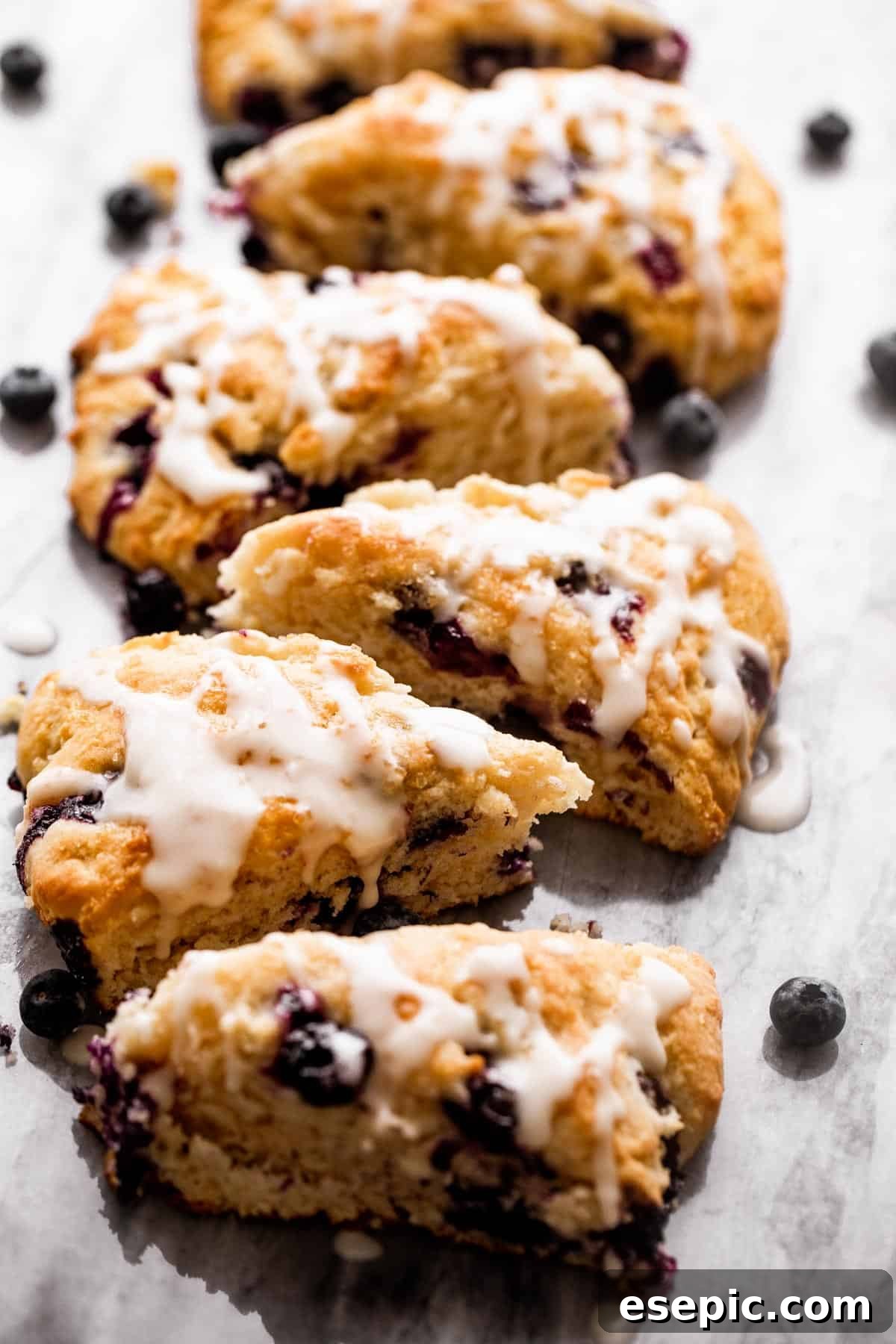 These Blueberry Scones are deliciously moist and easy to make with real, wholesome ingredients. six blueberry scones arranged in a single row on a marble board