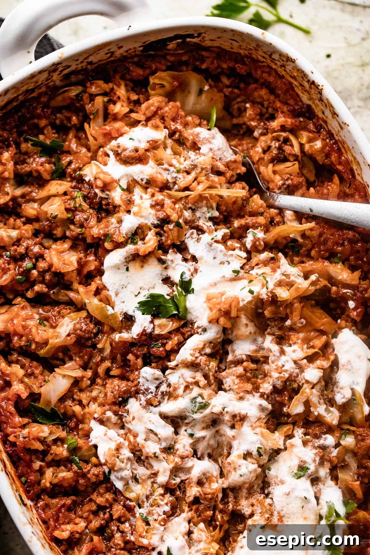 overhead shot of Cabbage Roll Casserole in a white baking dish, and the casserole is smothered with sour cream on top.