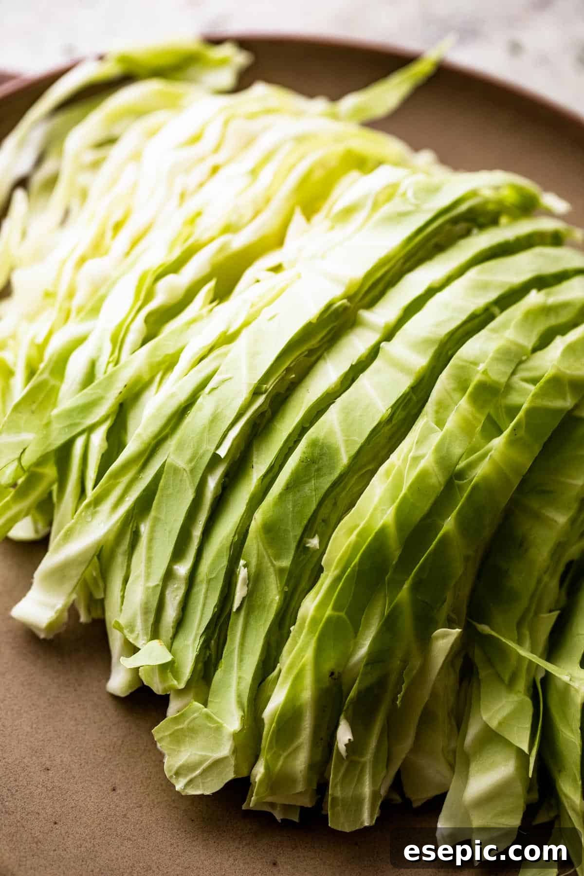 sliced green cabbage on a brown plate.