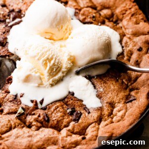 Close-up overhead shot of three vanilla ice cream scoops set on top of a large skillet cookie.