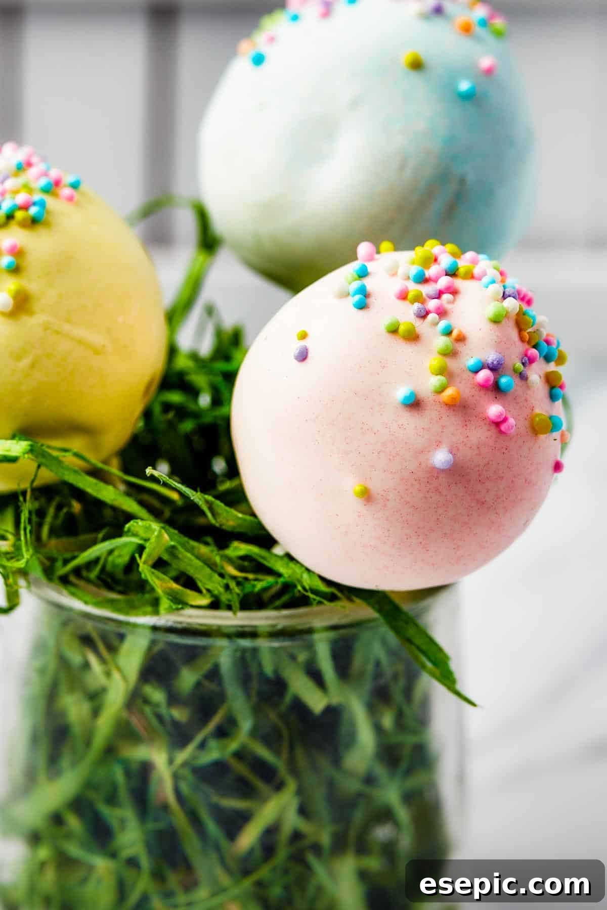 Pastel lollipops displayed beautifully in a white basket filled with festive Easter grass.