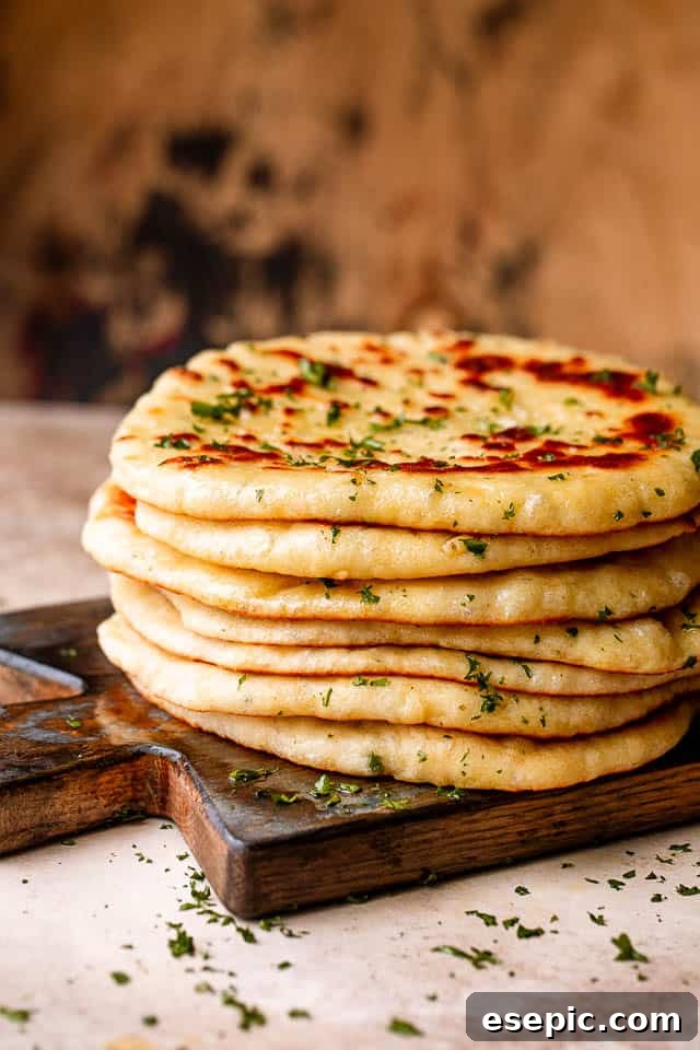 Stack of homemade flatbread on a wooden board, garnished with fresh parsley.
