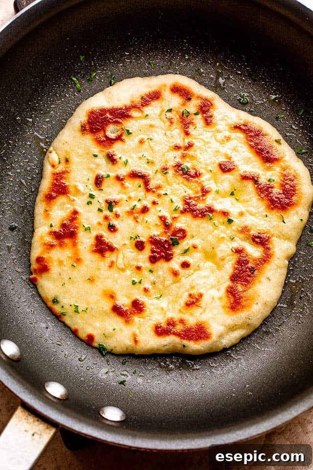 Homemade flatbread sizzling and puffing beautifully on a hot skillet.