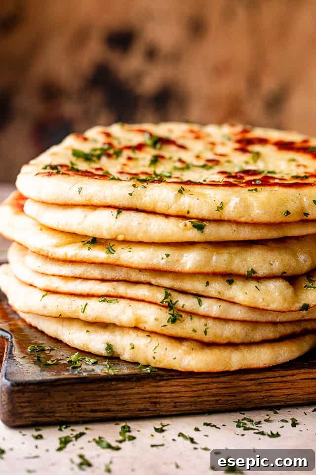 Stack of freshly made homemade flatbread on a wooden board, ready to be enjoyed.