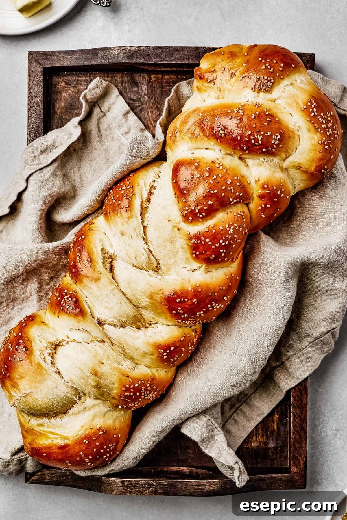 Fluffy, Golden, and Irresistible Challah Bread 2 Baked challah with sesame seeds, on a sheet pan with a tea towel, ready to be enjoyed.