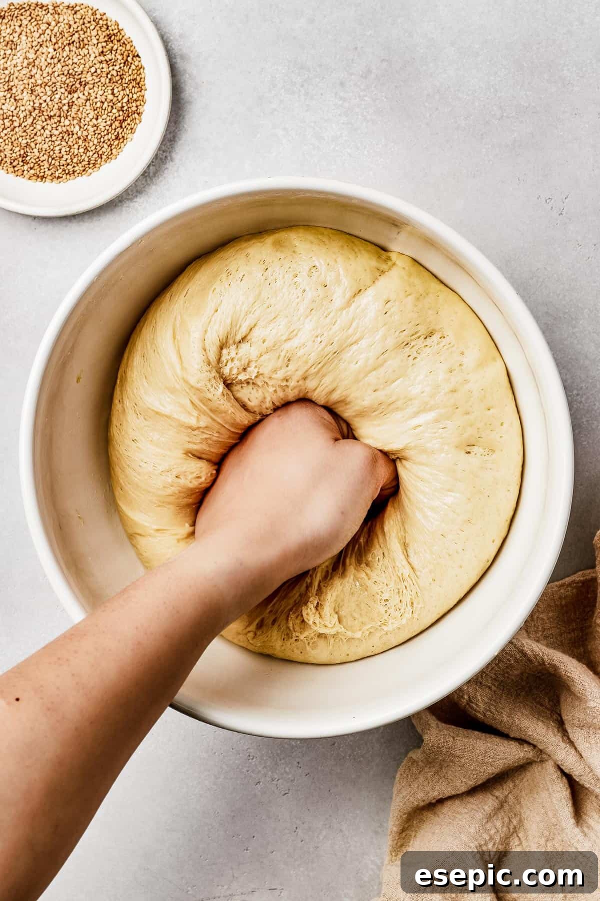 Fluffy, Golden, and Irresistible Challah Bread 6 Risen challah bread dough being gently punched down in the center to release air.