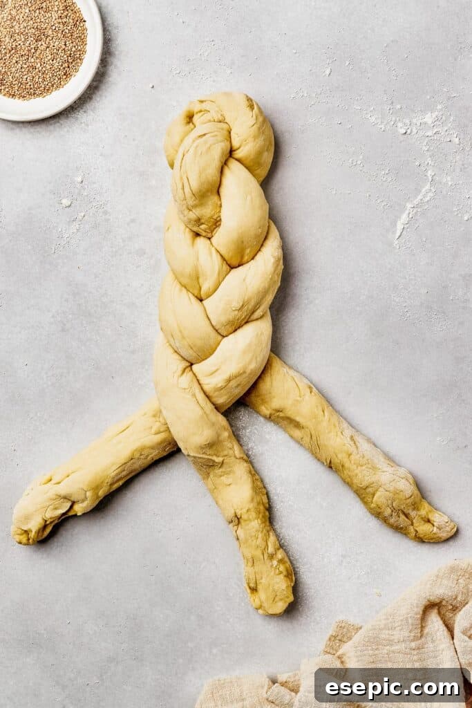 Fluffy, Golden, and Irresistible Challah Bread 7 Three long pieces of challah dough being braided together into a loaf.