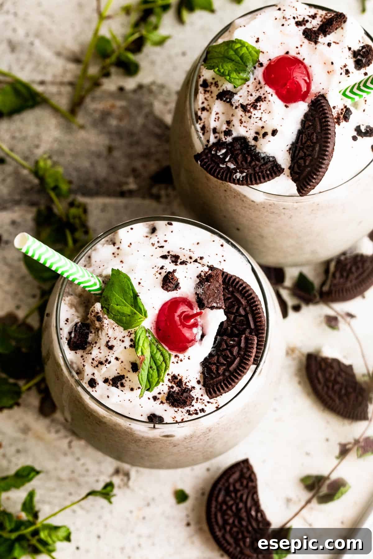 Shamrock Oreo Dream Swirl 5 two drinking glasses filled with Shamrock Oreo McFlurry Shake, topped with whipped cream, maraschino cherries, and mint leaves.