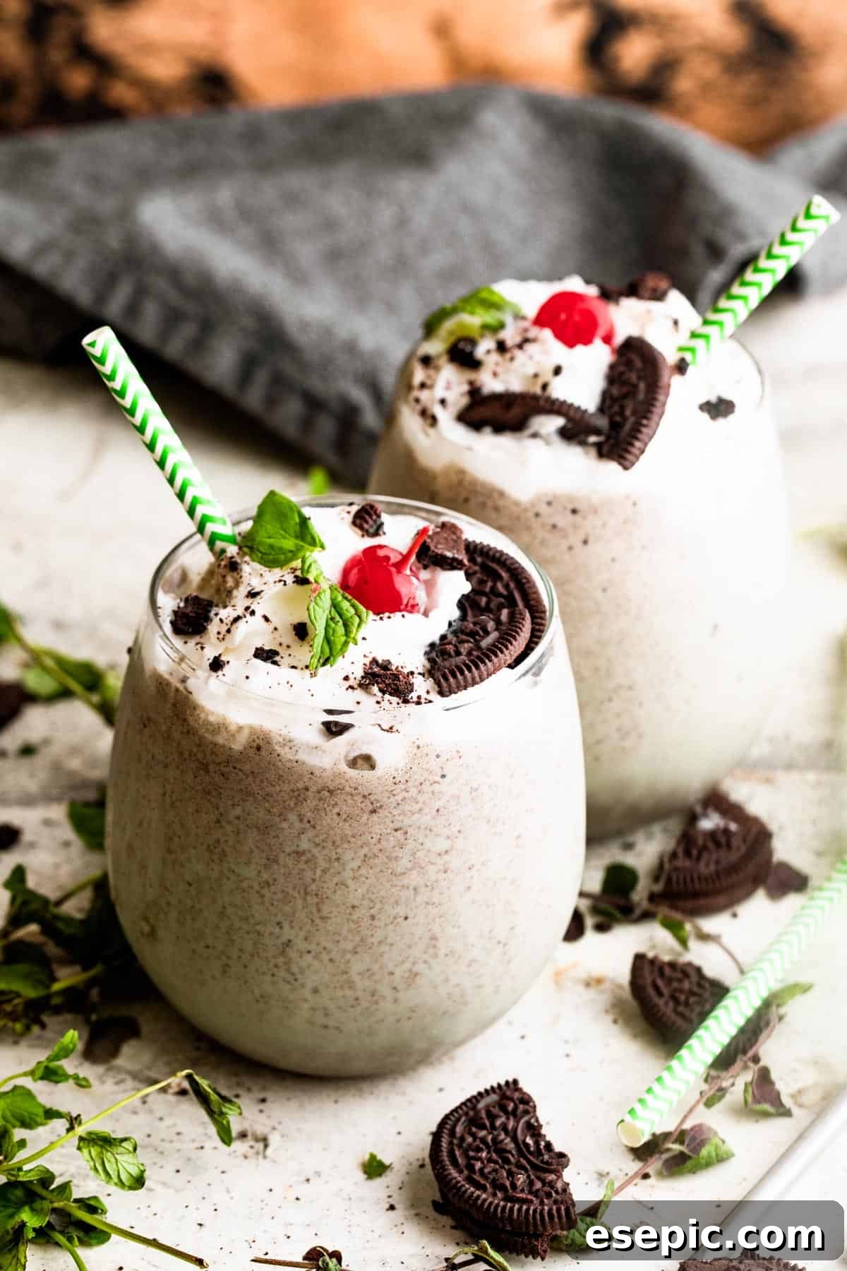 Shamrock Oreo Dream Swirl 6 two drinking glasses filled with Shamrock Oreo McFlurry Shake, topped with whipped cream, maraschino cherries, and mint leaves.
