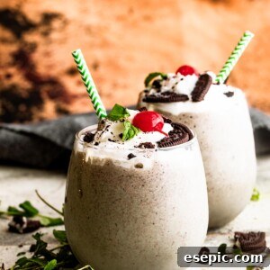 Shamrock Oreo Dream Swirl 7 two drinking glasses filled with Shamrock Oreo McFlurry Shake, topped with whipped cream, maraschino cherries, and mint leaves.