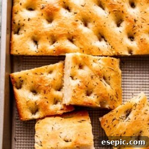 Overhead shot of freshly baked focaccia, golden brown and garnished with herbs.