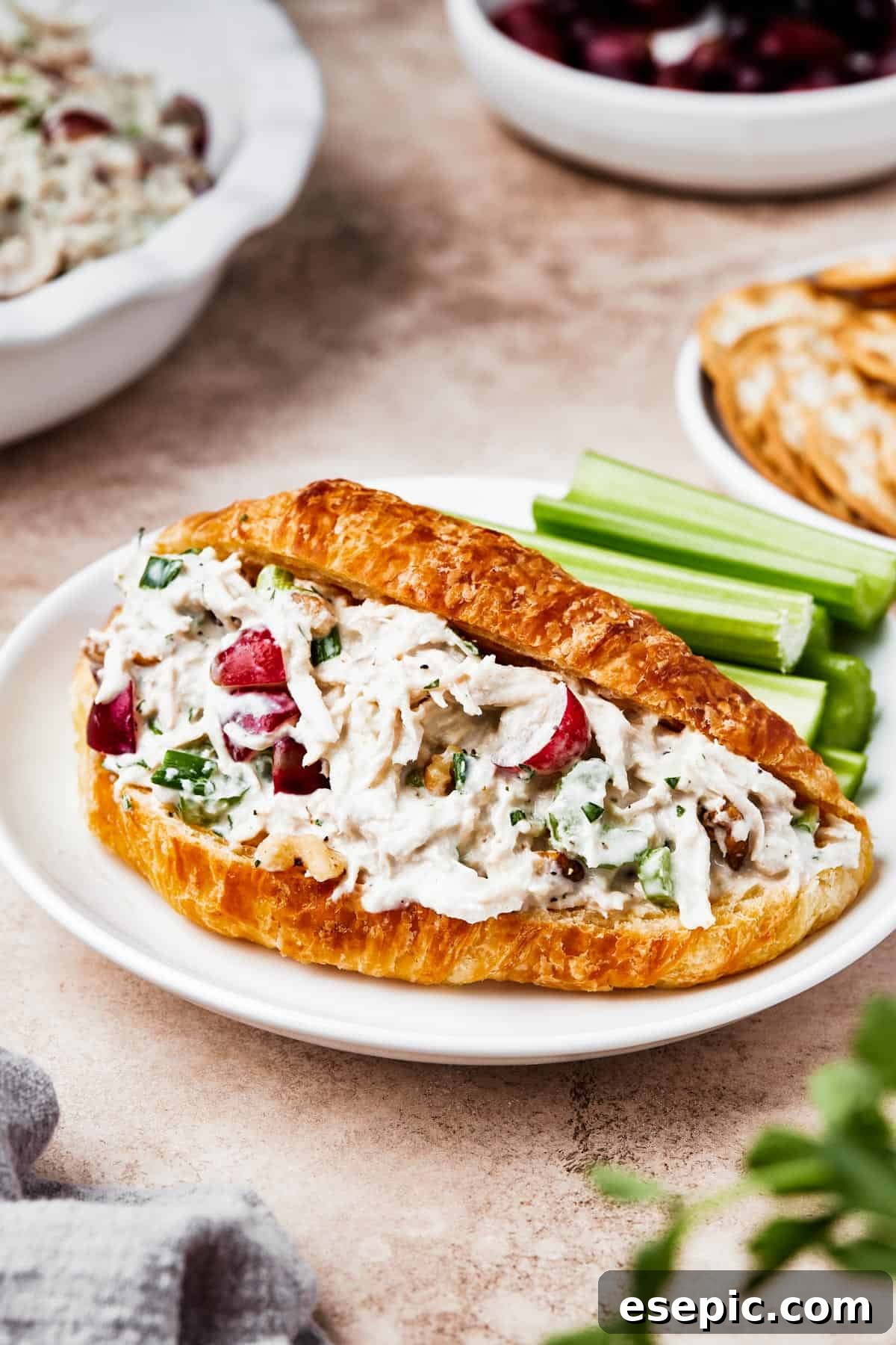 Chicken salad with grapes served in a split croissant on a wooden board.