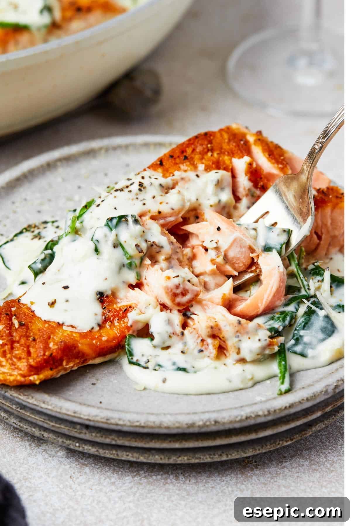 A beautifully plated dish of Salmon Florentine, highlighting the succulent salmon fillet with a generous coating of creamy spinach sauce.