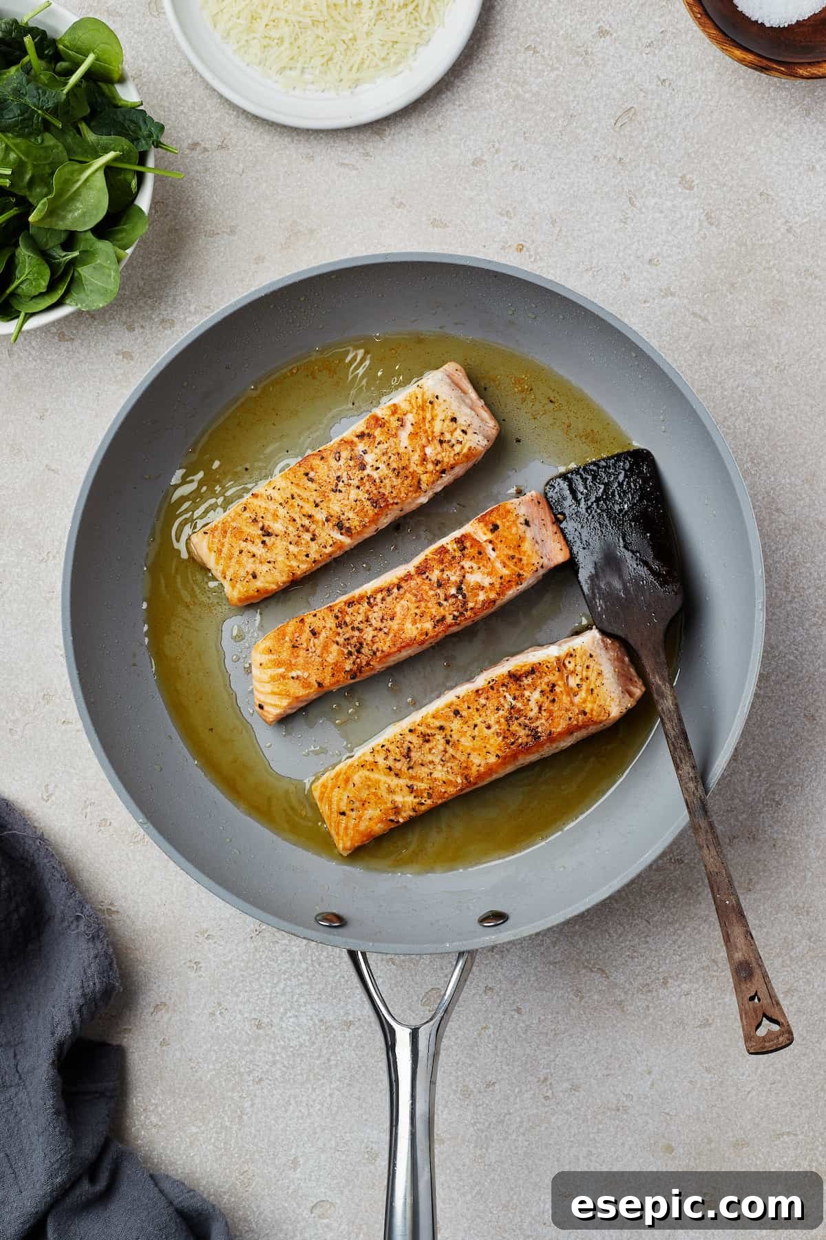 Salmon fillets being pan-fried to a golden crisp in a hot skillet, ready for the sauce.