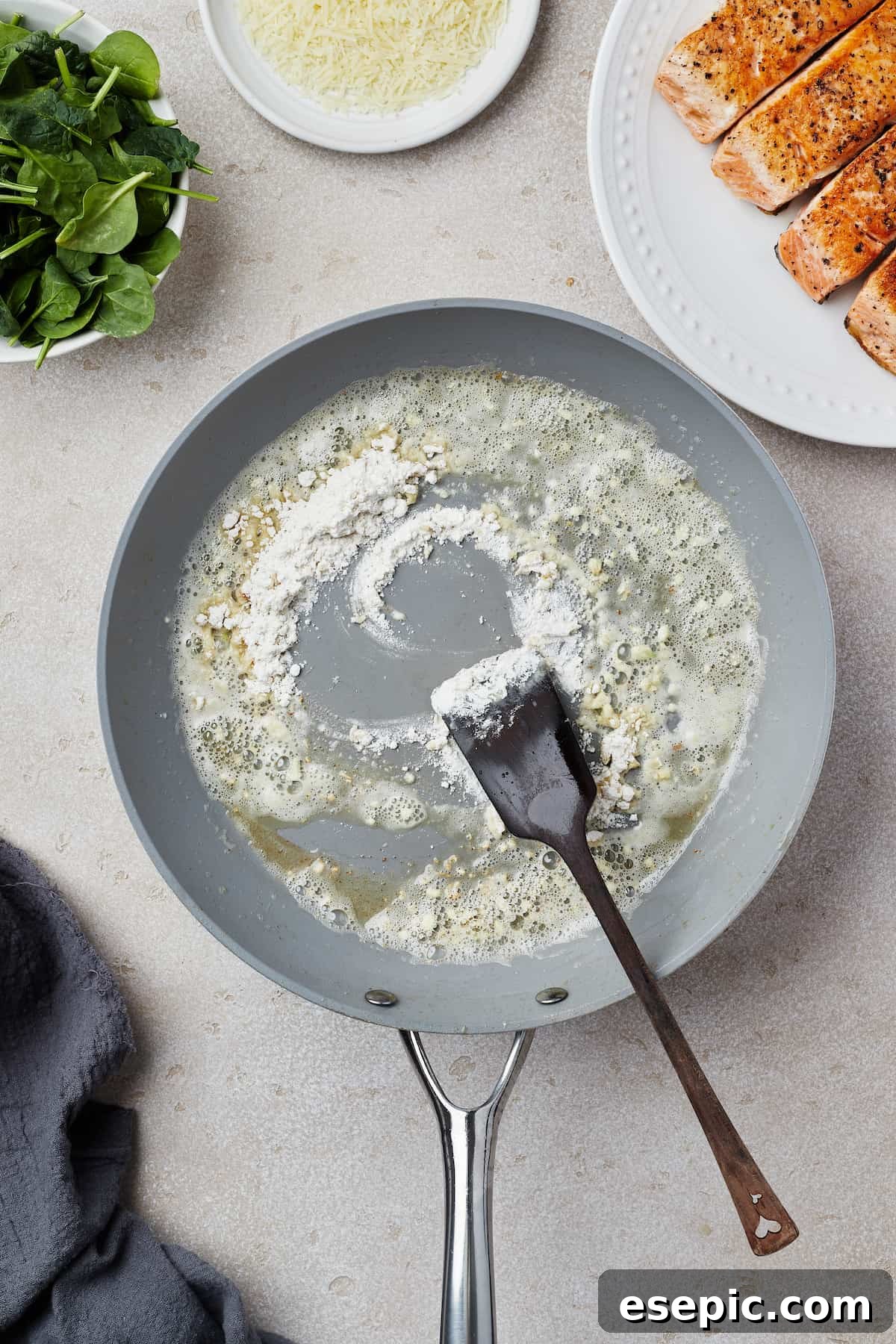 A skillet showing melted butter, fragrant minced garlic, and flour cooking together to form a rich roux base for the Florentine sauce.