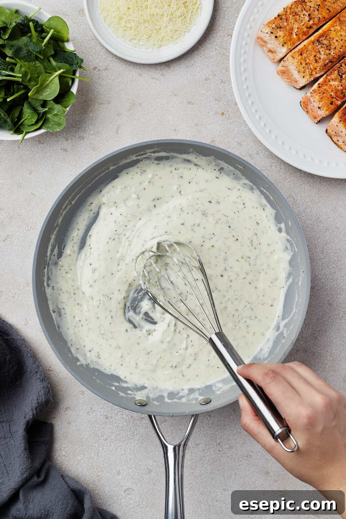 A creamy, white sauce being vigorously whisked in a skillet, ensuring a smooth, lump-free consistency.