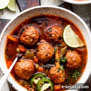 overhead shot of two soup bowls filled with albondigas soup and garnished with limes and sliced jalapenos.