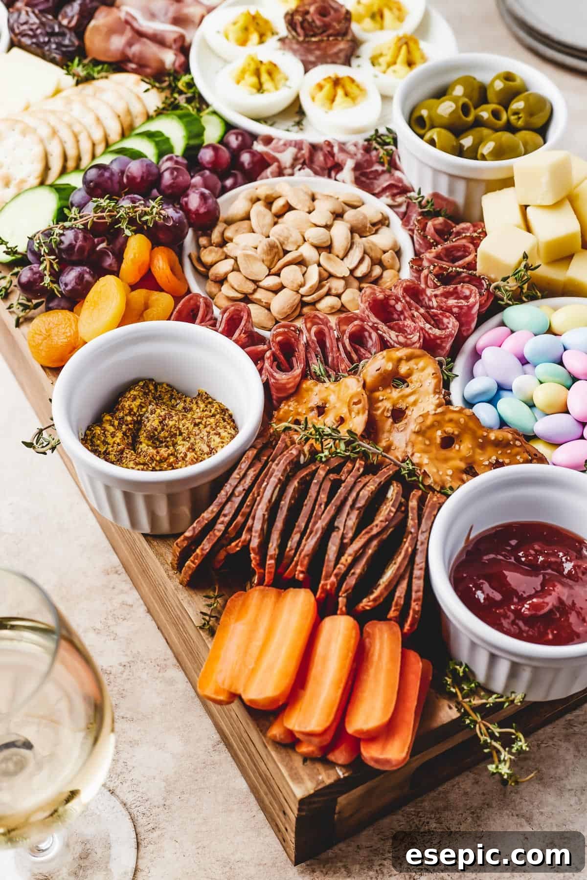 Close-up shot of a cutting board arranged with marcona almonds, grapes, dried apricots, baby carrots, fig crackers, and more.